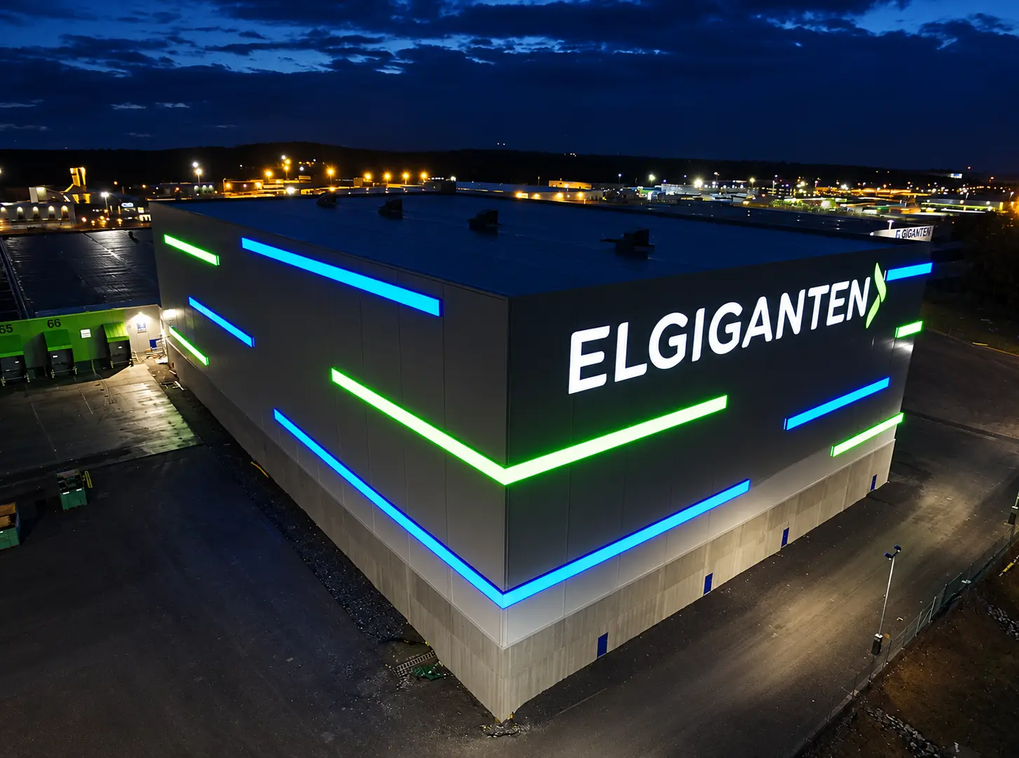 Stor belyst dukskylt för Elgiganten på en logistikbyggnad i kvällsljus