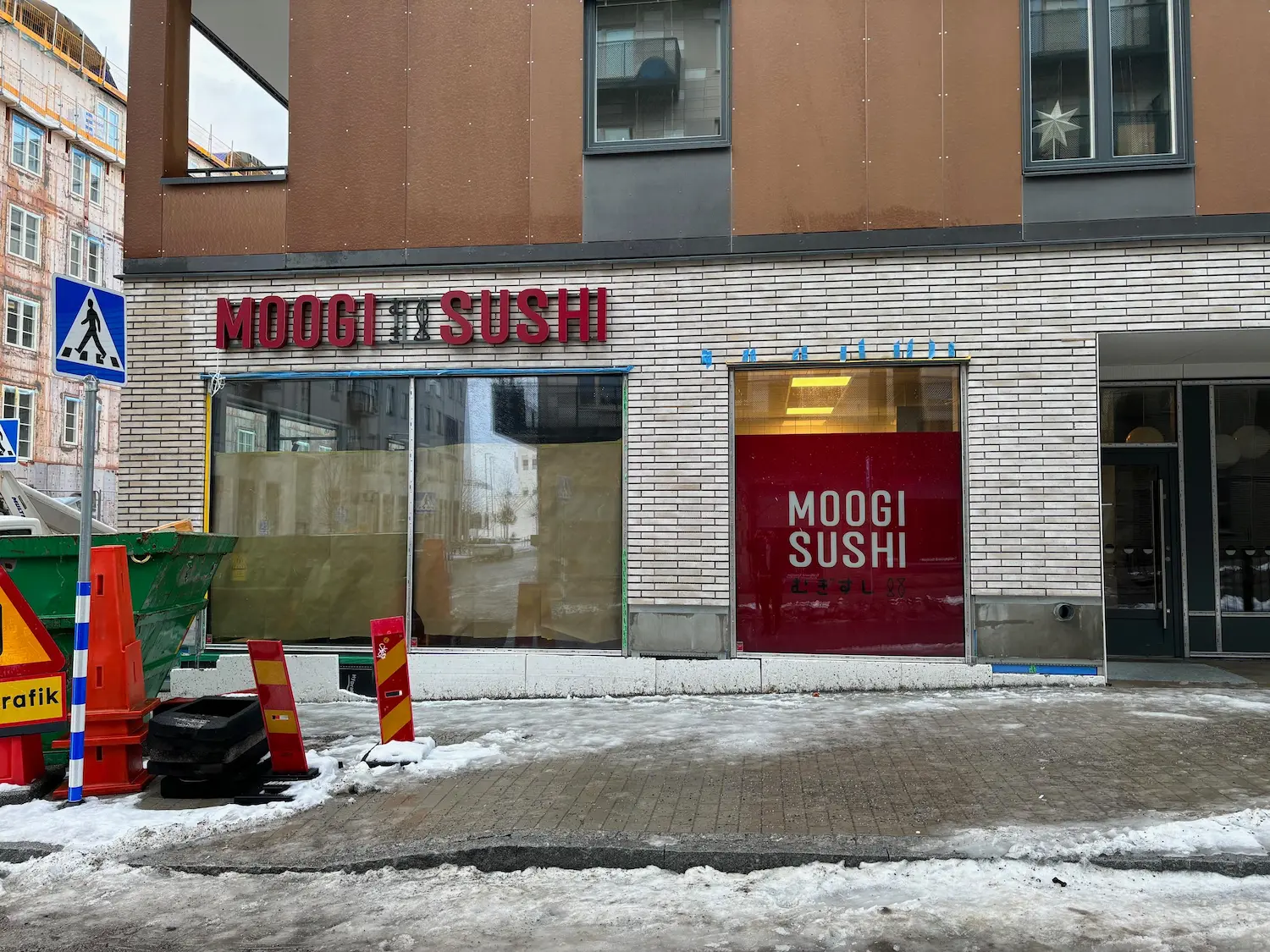 Röda belysta profilbokstäver för Moogi Sushi ovanför butiksentrén