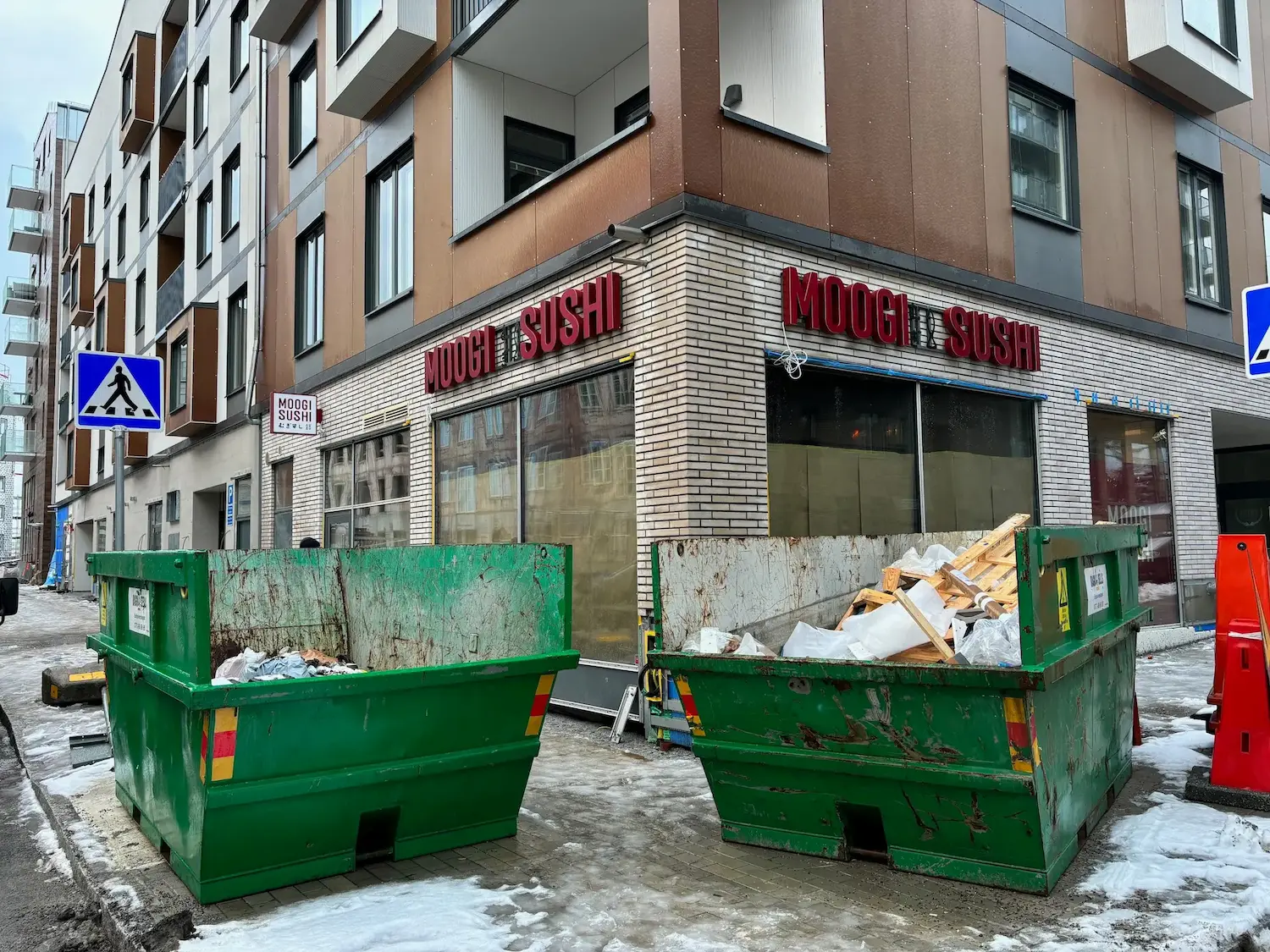 Röda belysta profilbokstäver för Moogi Sushi på hörnlokal i stadsmiljö