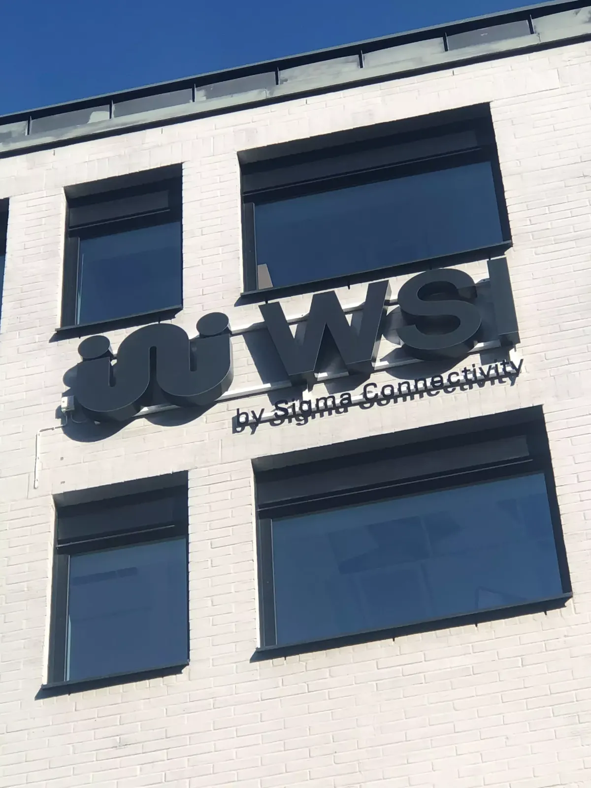 Fasadskylt för Sigma Connectivity WSI på kontorsbyggnad i Kista
